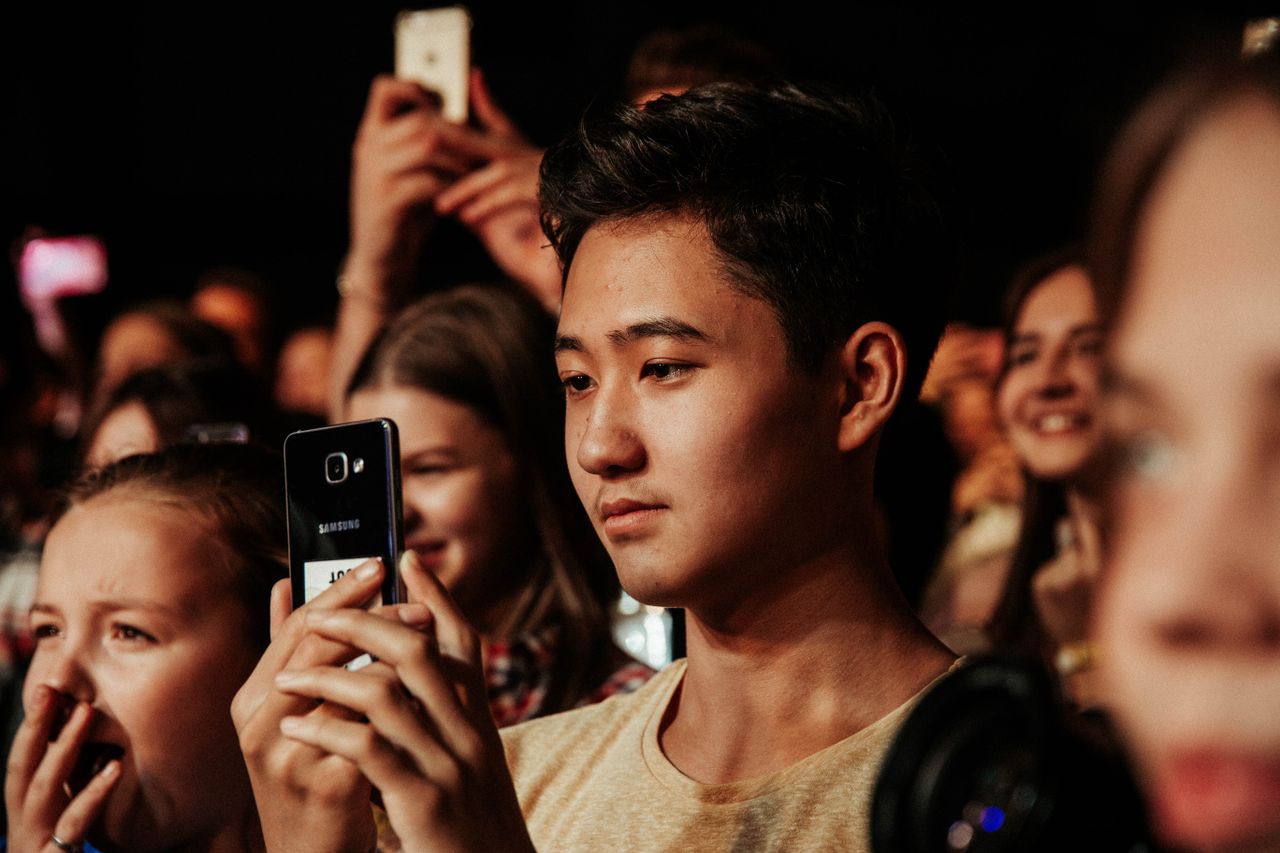 Menu A group of young concert-goers capturing memorable moments with smartphones.